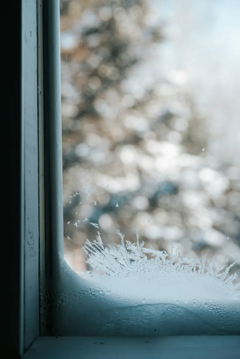 Cristal frío con escarcha y señales de condensación durante el invierno en una vivienda